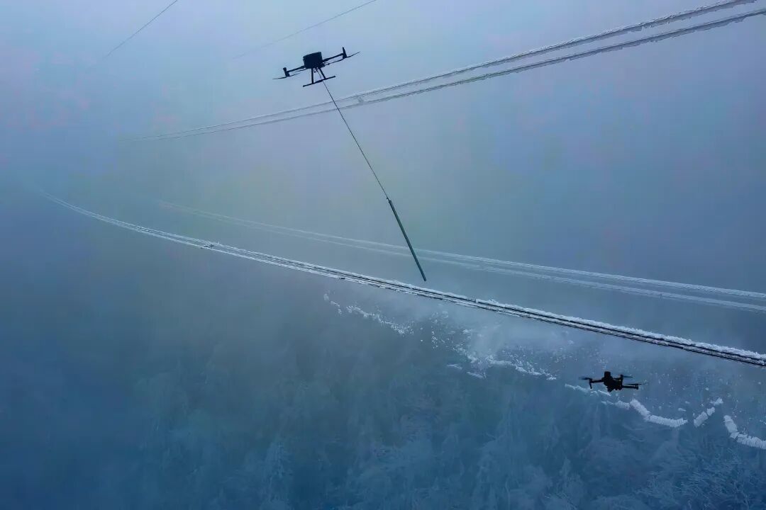 《无人机重“棒”出击保供电》2025年2月2日,在湖北十堰市茅箭区大川镇五条岭,国网十堰供电公司运维人员在220千伏十房线17~18号杆塔开展无人机除冰作业。郝金鑫 摄.jpg