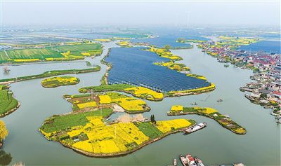 工作人员在江苏泰州海陵区华港镇下溪村乘船巡检水上光伏设备。汤德宏摄(人民视觉)