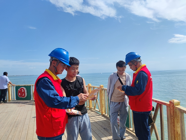6月23日，国网博湖县供电公司员工巴音达来、阿力米热提·阿不都热合曼为开湖季捕鱼节开幕保点护航，向游客发放安全用电手册。（王坤） (3)_副本.jpg